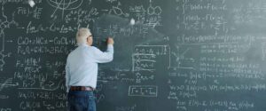 Selbststaendig als Fahrzeugaufbereiter Rechenbeispiel - Professor steht vor Tafel und rechnet Formeln aus