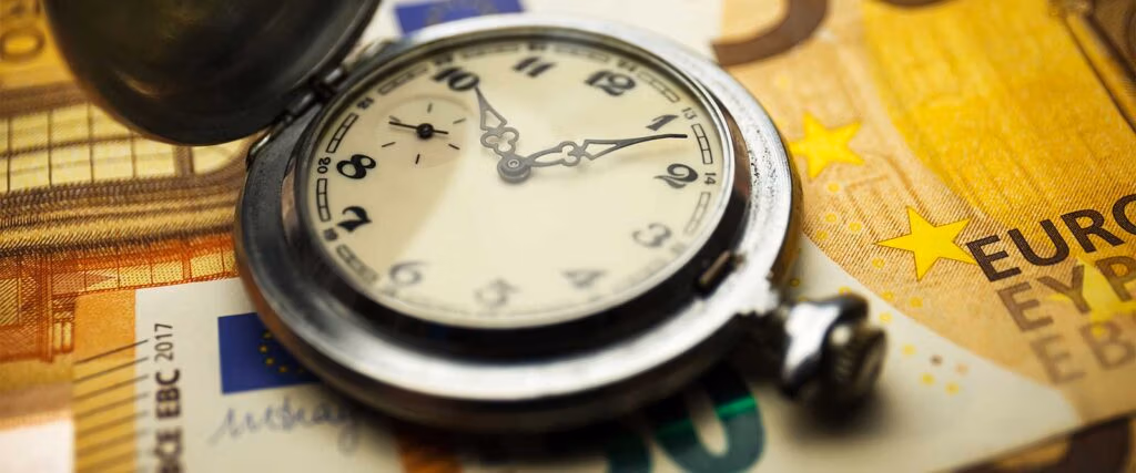 Stundenlohn berechnen als Fahrzeugaufbereiter - Uhr mit Gelscheinen auf einem Tisch