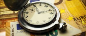Stundenlohn berechnen als Fahrzeugaufbereiter - Uhr mit Gelscheinen auf einem Tisch